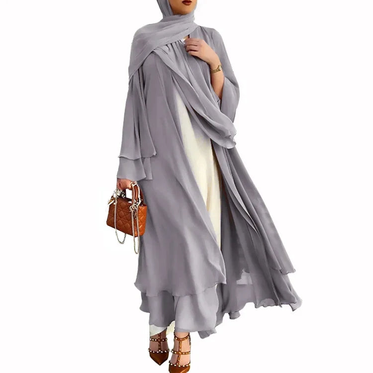 Woman wearing a gray hijab and white dress with a brown handbag on a white background