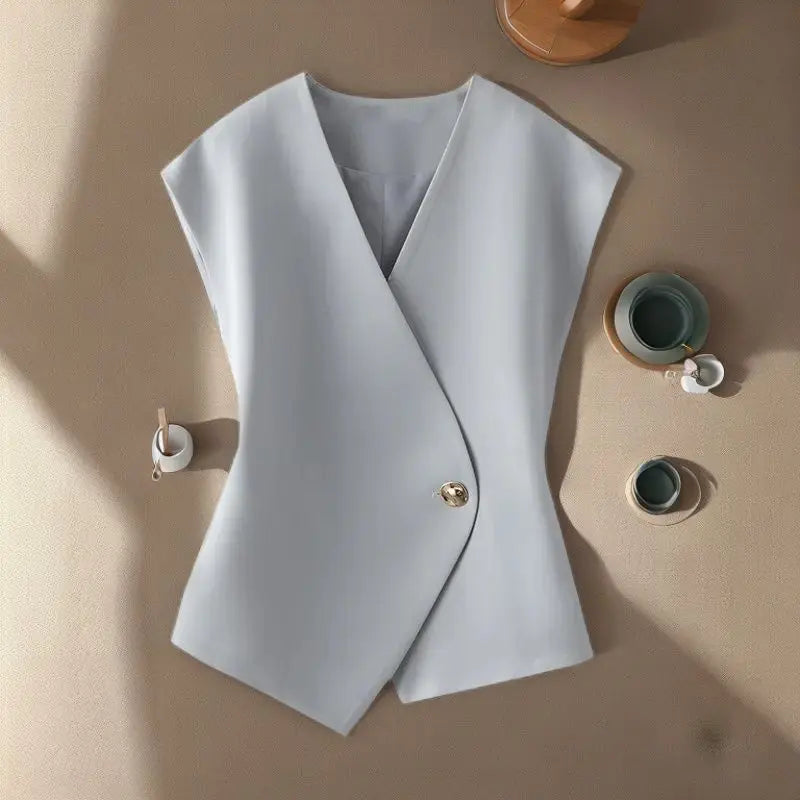 Light blue vest on a beige surface with small decorative items.