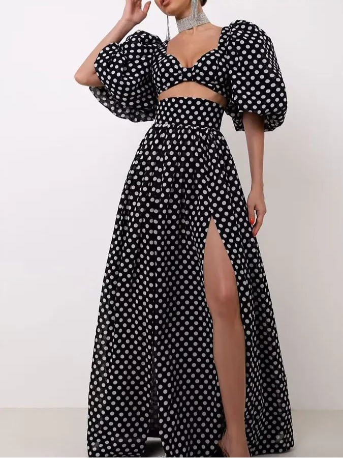 Woman wearing a black and white polka dot outfit with a high slit, posing against a white background with 'Trafza' branding.
