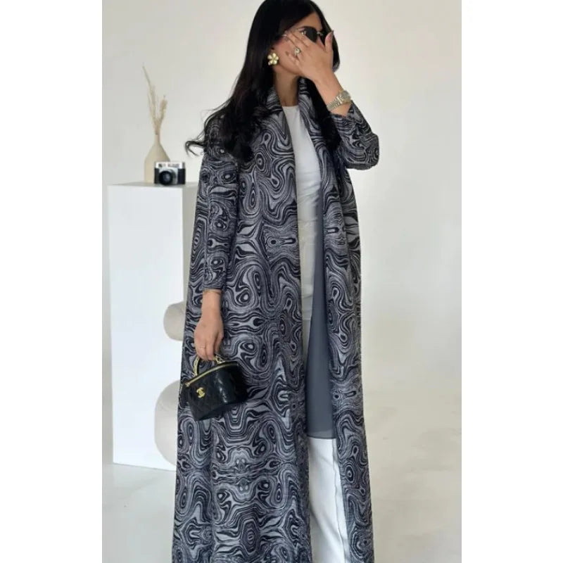 Woman wearing a long, patterned coat in a minimal indoor setting