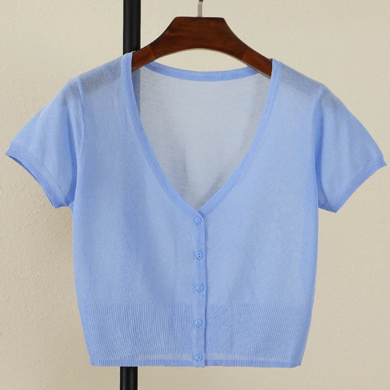 Light blue knit cardigan on a wooden hanger against a beige background