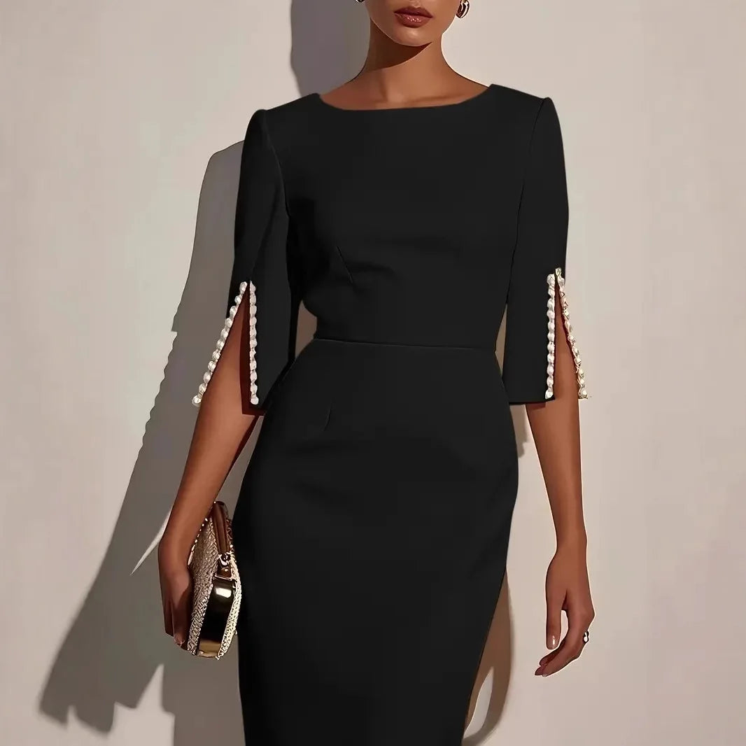 Black dress with pearl embellishments on sleeves against a neutral background