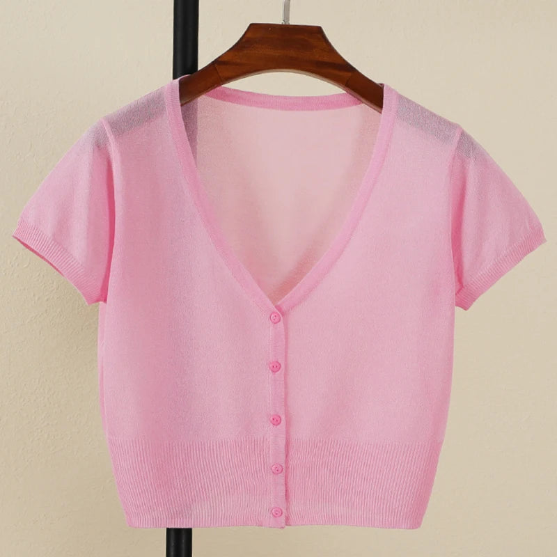 Pink short-sleeve cardigan on a hanger against a beige background
