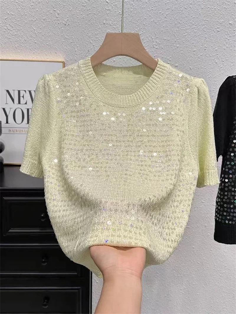 Light green sequin sweater on a hanger against a neutral background