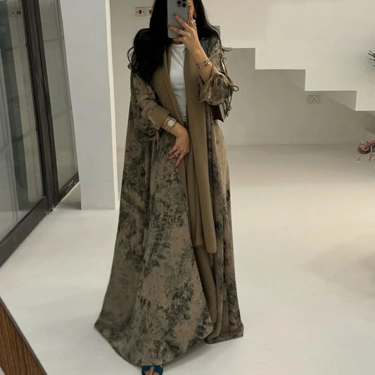 Person wearing a long floral dress with a beige cardigan in a minimalistic indoor setting.
