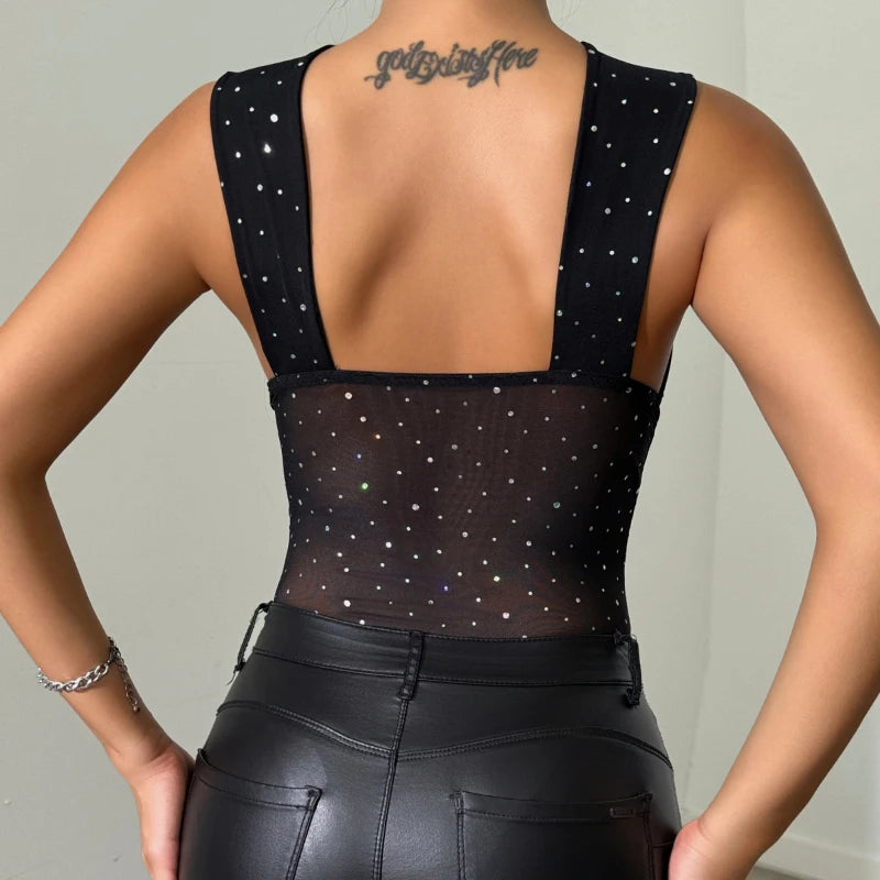 Person wearing a black bodysuit with star patterns and leather pants against a neutral background