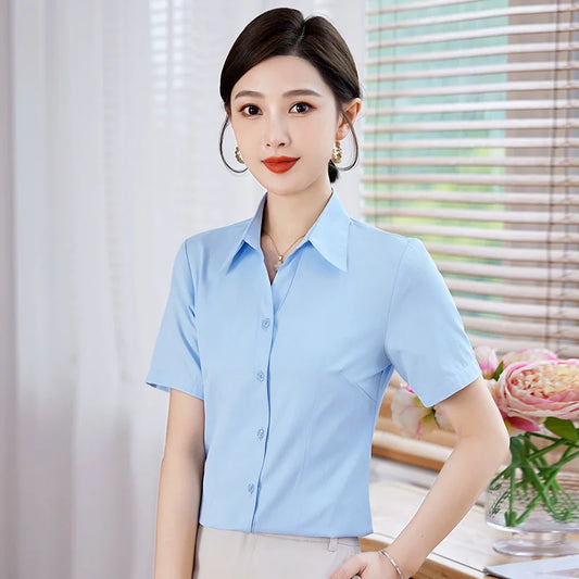 Woman wearing a light blue shirt in an indoor setting with flowers in the background