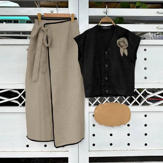 Beige skirt, black top with a brown bow, and brown clutch on a white background