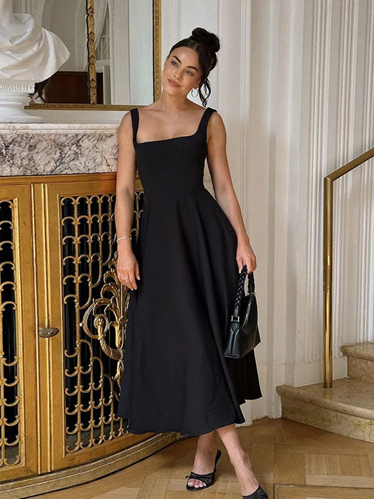 Woman in a black dress standing in an elegant interior setting