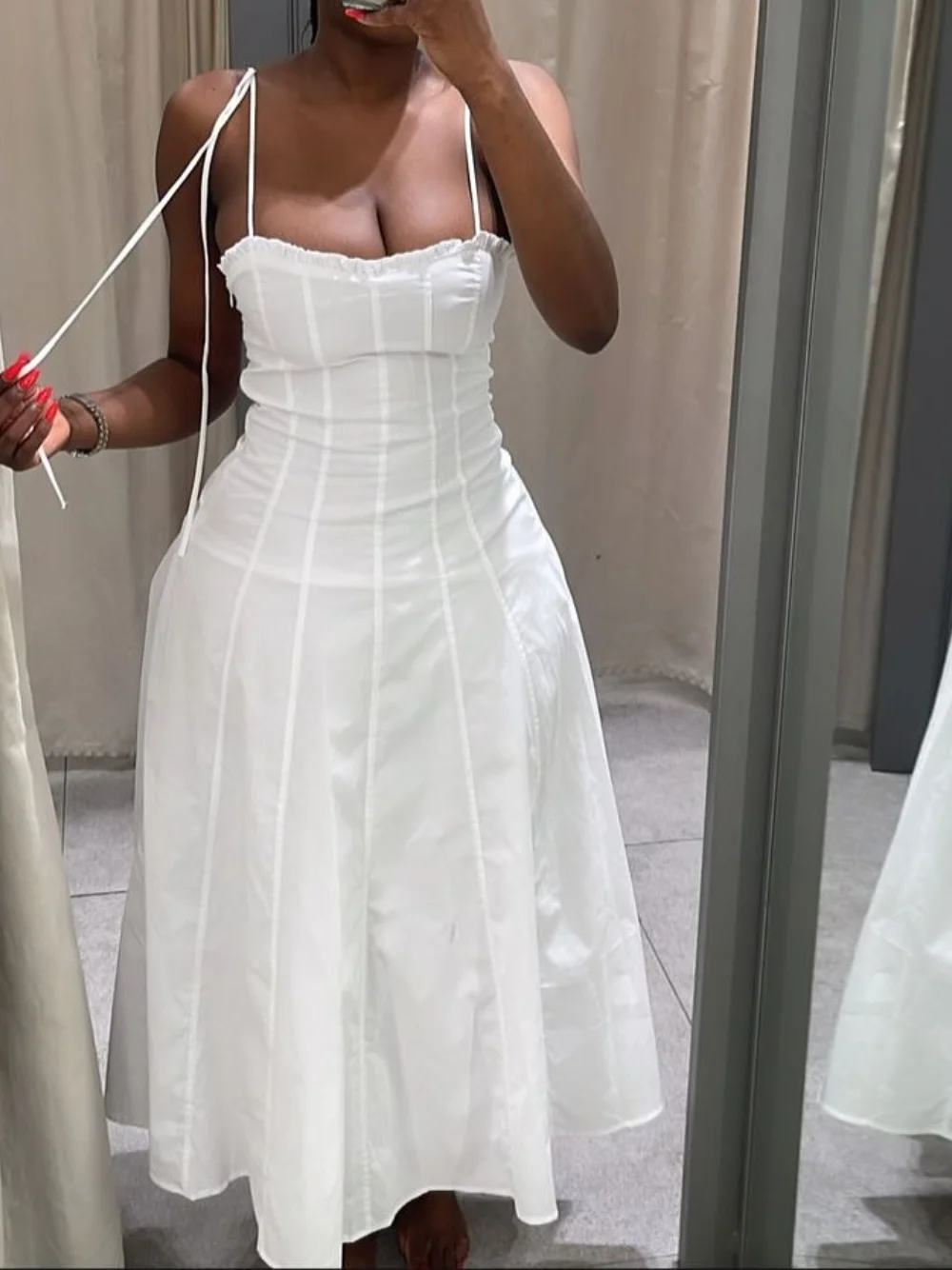 White strapless dress being tried on in a mirror.
