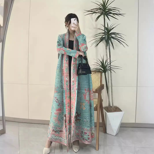 Woman taking a mirror selfie wearing a long, patterned dress in an indoor setting with a plant.