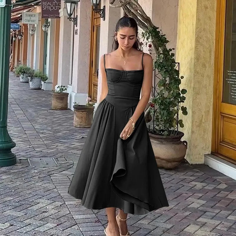 Woman in a black dress standing on a street with shops and plants in the background