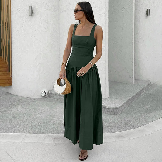 Woman wearing a green dress holding a small bag in an urban setting.