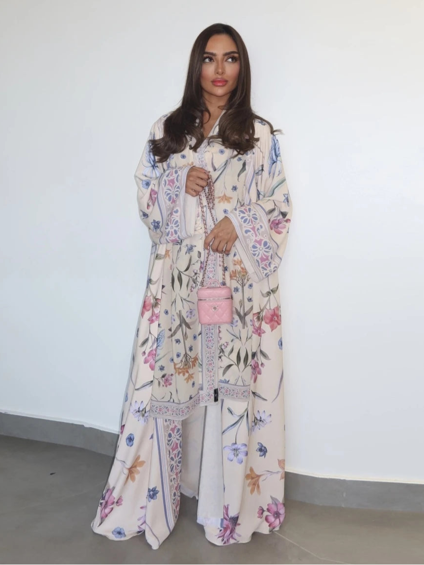 Woman wearing a floral outfit with a pink handbag against a white wall