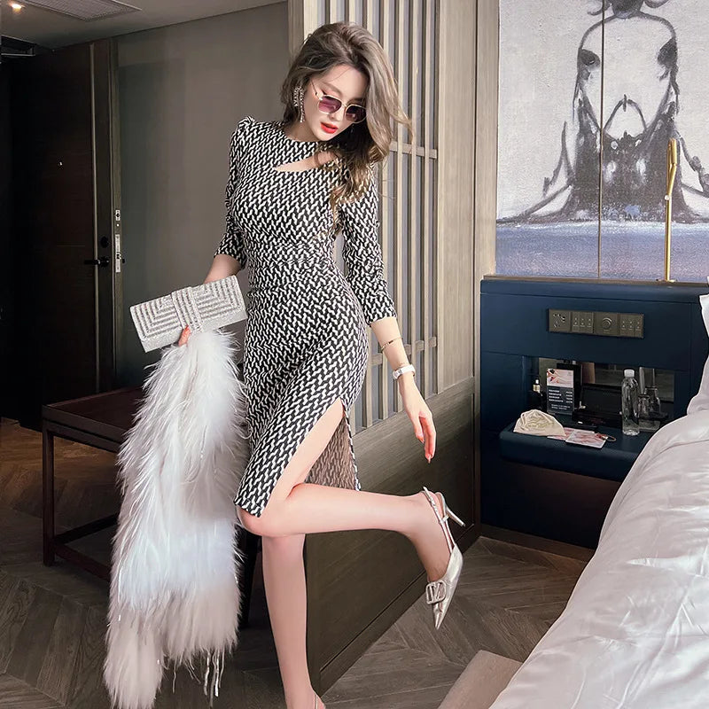 Woman in a patterned dress holding a fur coat in a room with a painting on the wall.