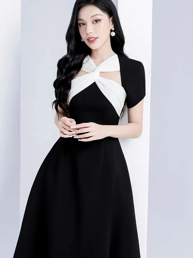 Woman wearing a black and white dress against a plain background