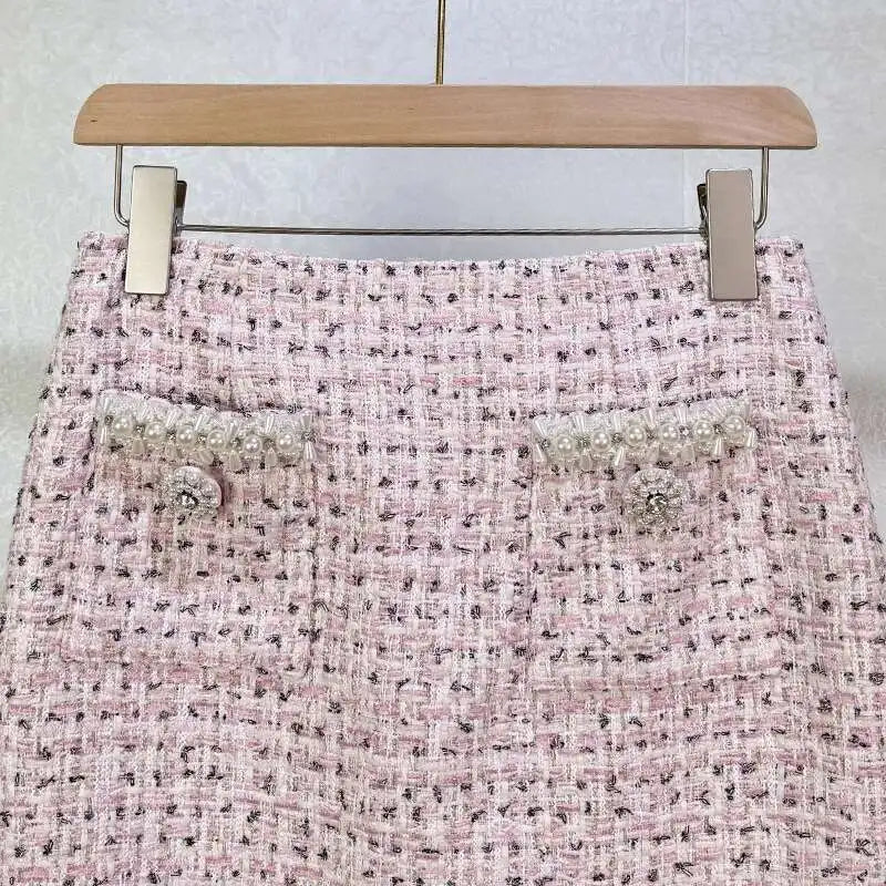 Pink tweed skirt with decorative buttons on a wooden hanger against a light background