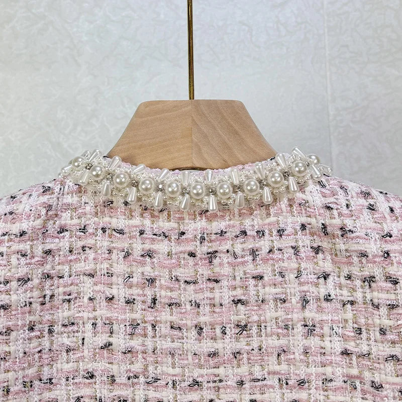 Mannequin wearing a pink and black patterned garment with pearl embellishments against a white background