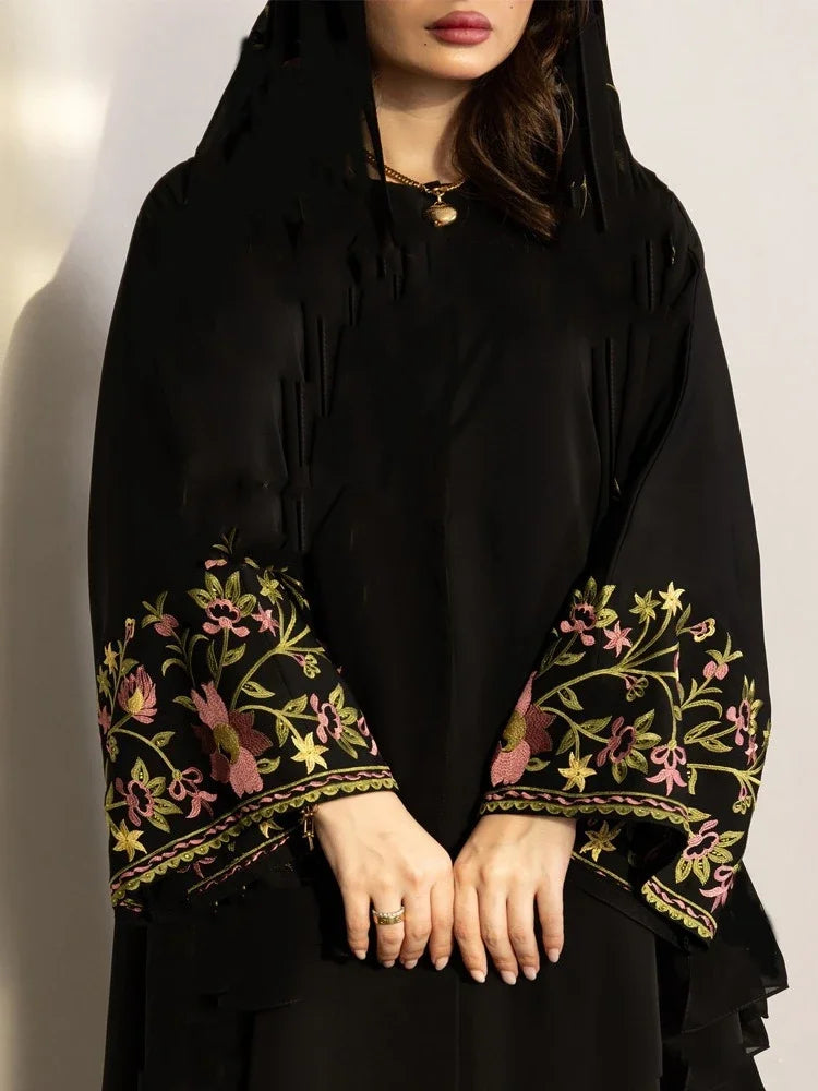 Black embroidered garment with floral patterns on a plain background
