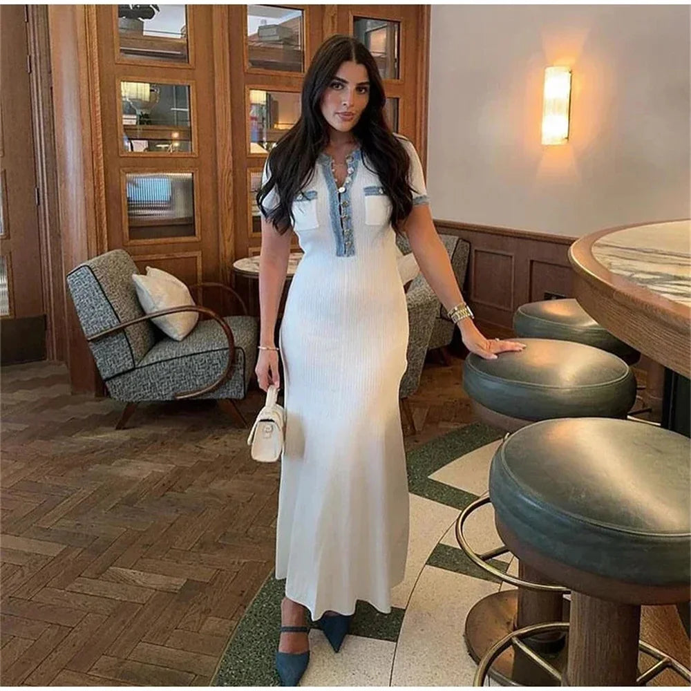 Woman in a white dress standing in a stylish interior setting with wooden floors and modern decor.