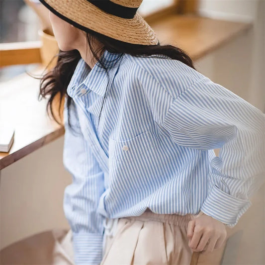 Person wearing a blue striped shirt and beige hat indoors
