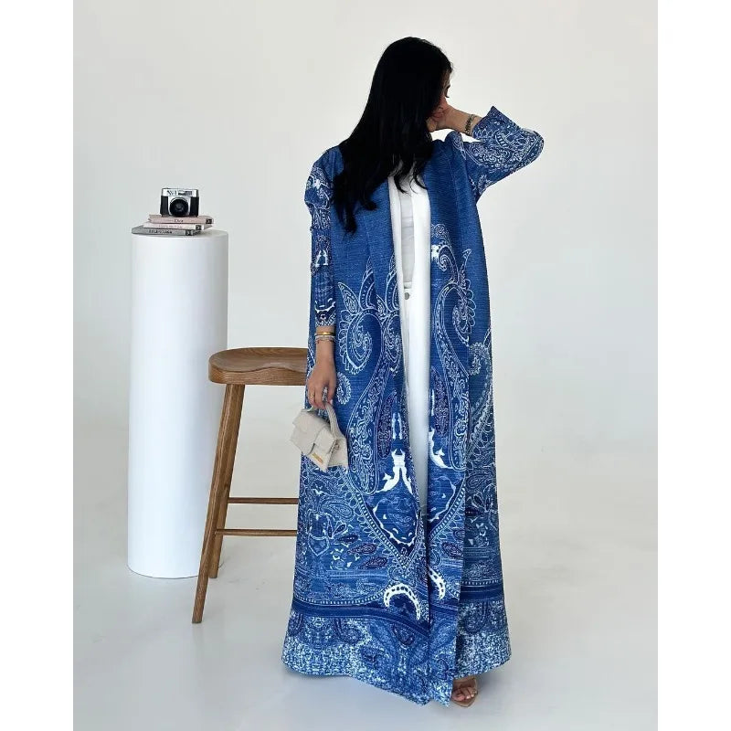 Woman wearing a blue patterned dress standing in a minimalistic setting.