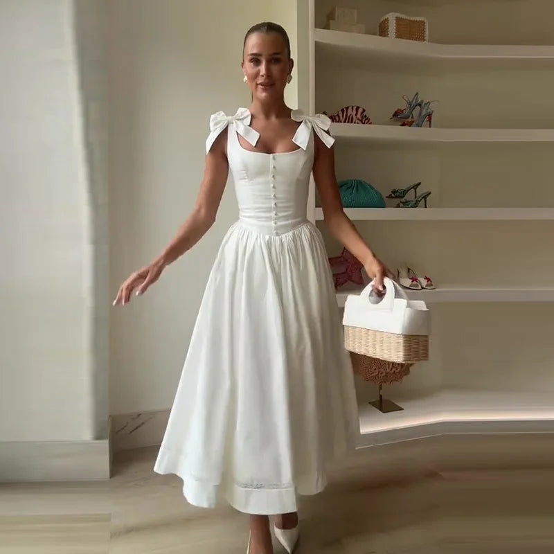 Woman in a white dress holding a basket in a room with shelves.