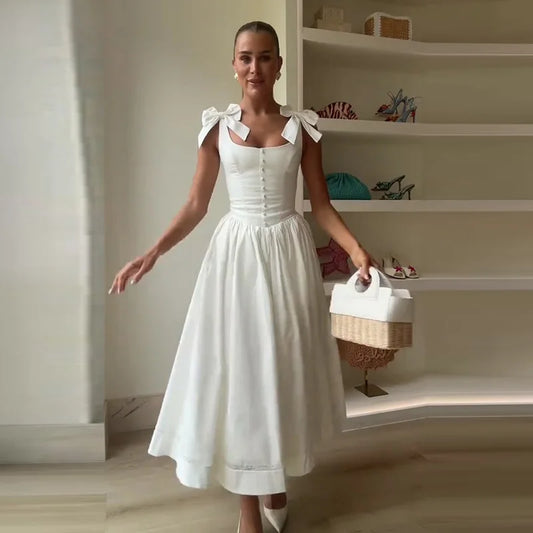 Woman in a white dress holding a basket in a room with shelves.