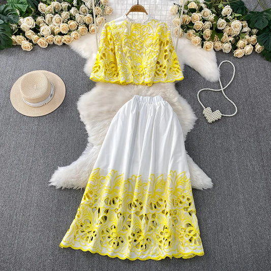 Yellow and white lace top and skirt set on a gray surface with decorative elements.