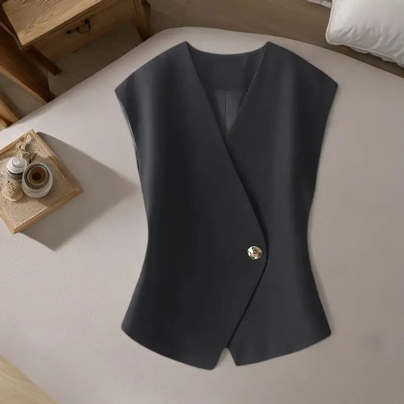 Black vest with a button on a bed in a bedroom setting