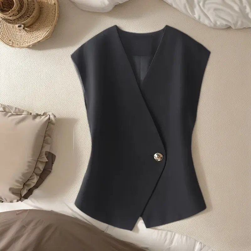 Black vest with a button on a beige surface
