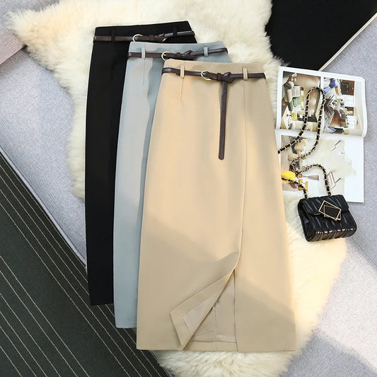 Three skirts in black, gray, and beige with a belt on a textured surface.