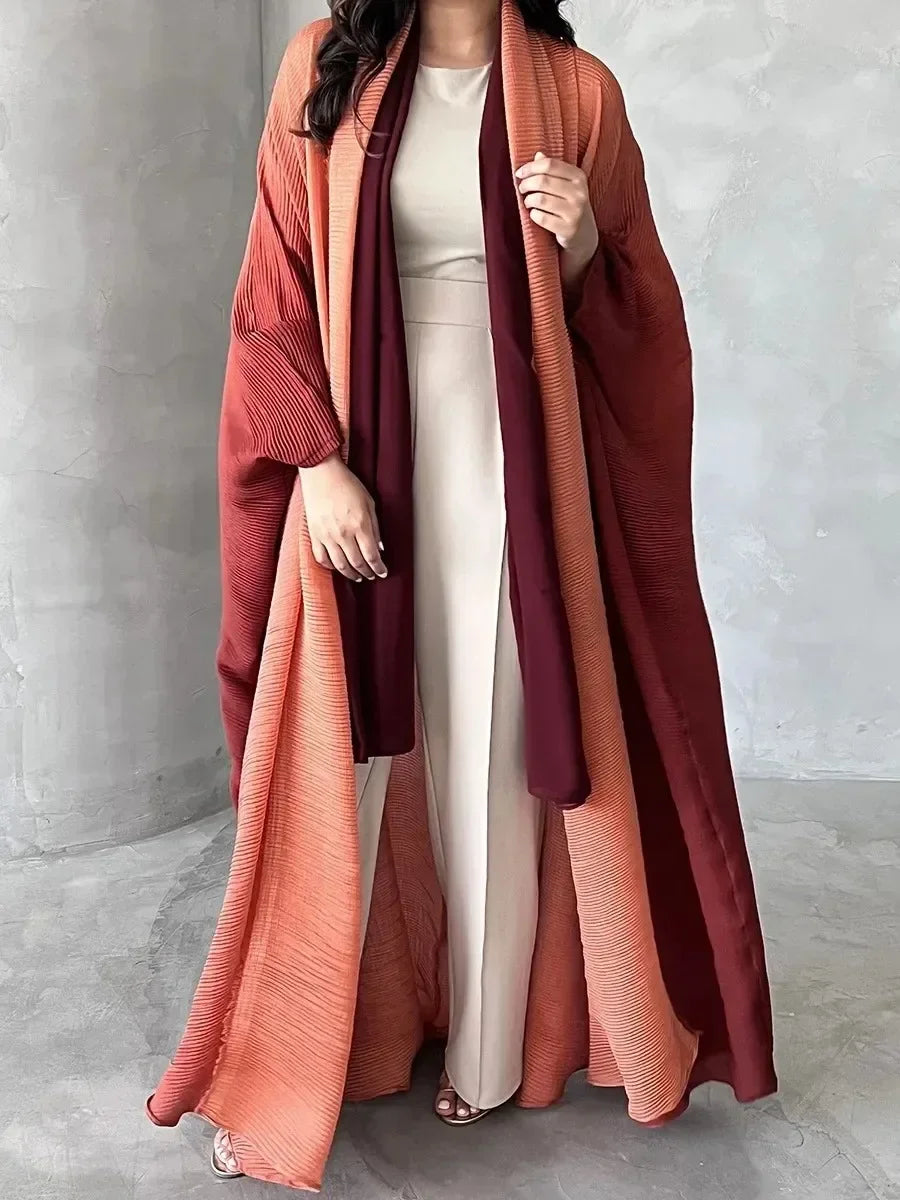 Person wearing a long, flowing garment with a gradient of colors against a plain background