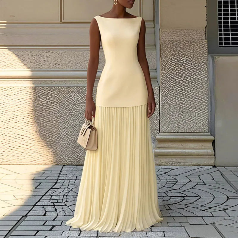 Woman wearing a long beige dress standing on a stone pavement.