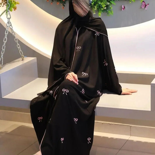 Black garment with white embroidery on a mannequin against a neutral background