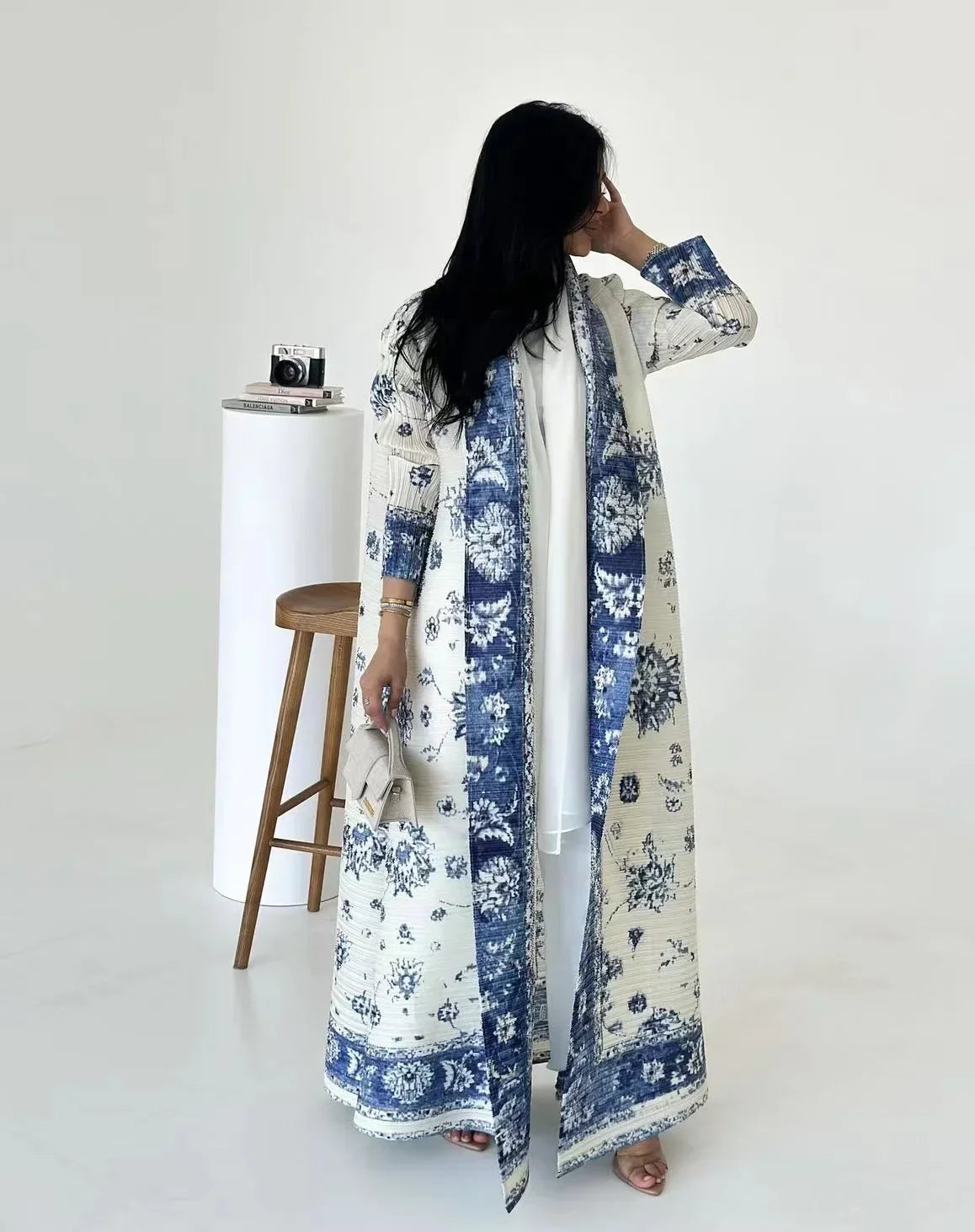 Woman wearing a long, floral-patterned dress against a white background