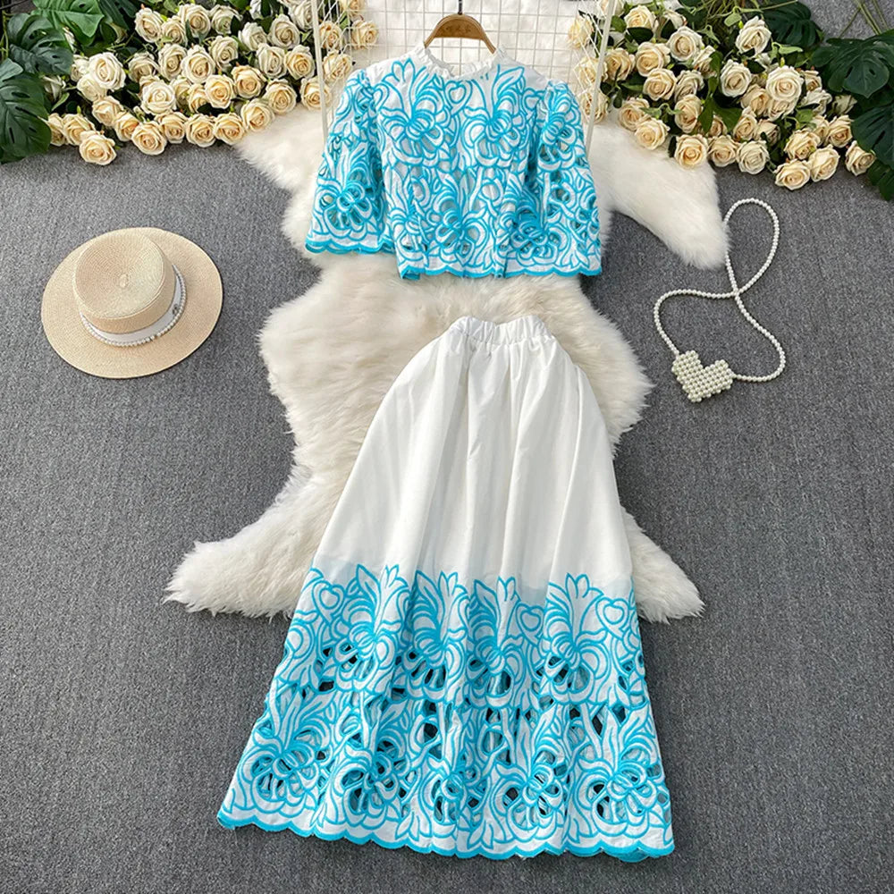 Blue and white lace top and skirt set on a gray surface with decorative elements.