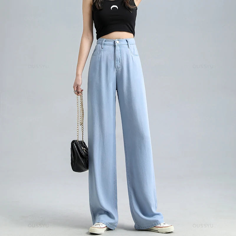 Person wearing light blue jeans and a black top on a gray background
