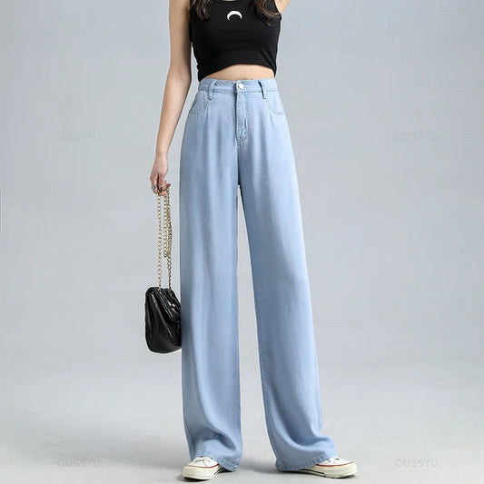 Person wearing light blue jeans and a black top on a gray background