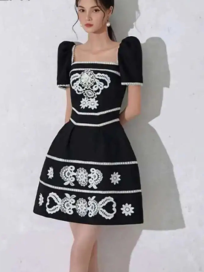 Black dress with white embroidery on a white background, featuring the brand 'DEAT'.