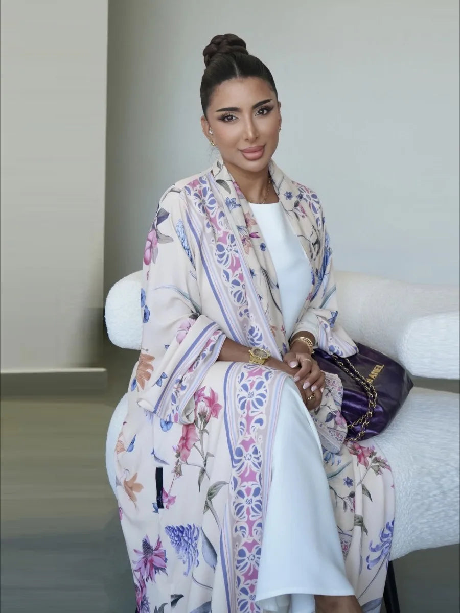 Woman sitting on a white couch wearing a floral dress with a plain background