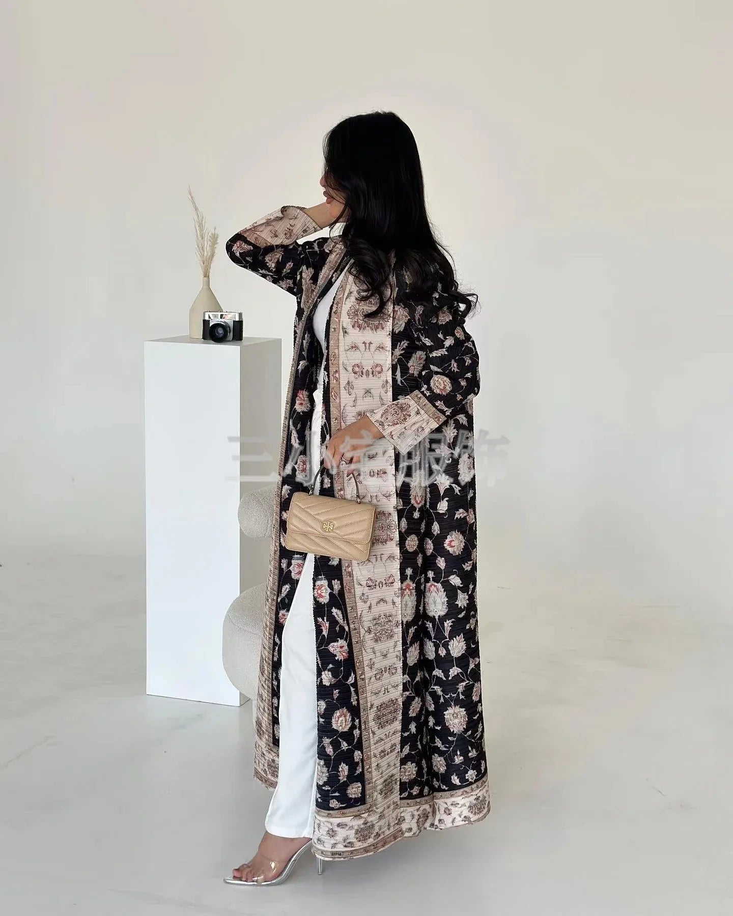 Woman wearing a long, patterned coat with a neutral background