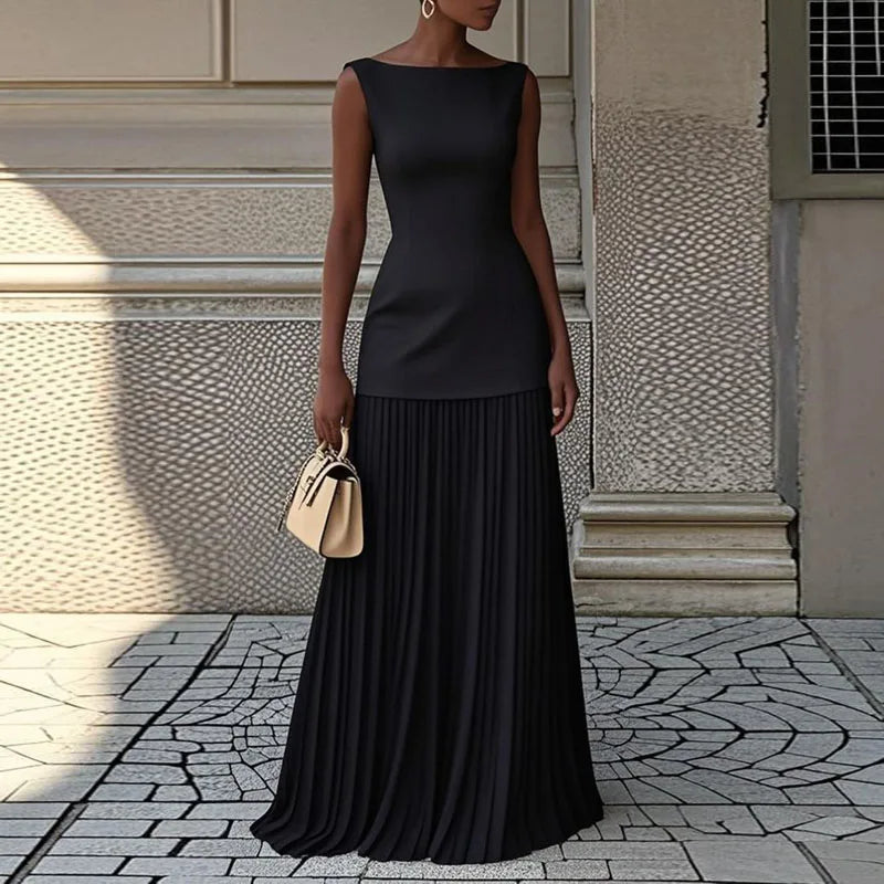 Woman wearing a black dress standing on a stone pavement with a textured wall background