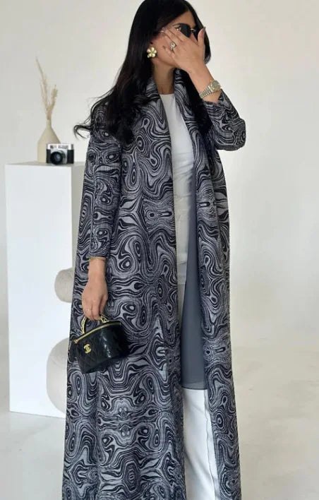 Woman wearing a long, patterned coat against a white background