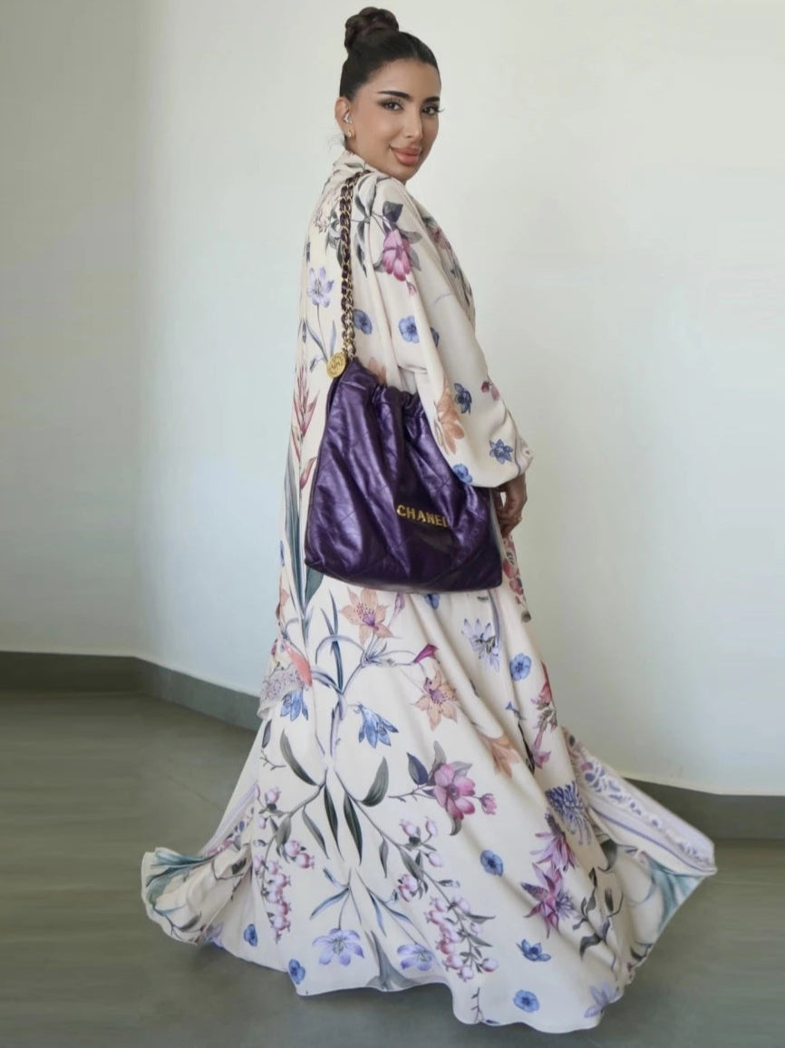 Woman in a floral dress holding a purple handbag against a plain background