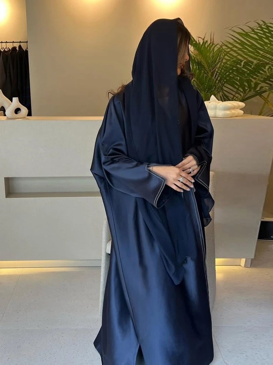 Person wearing a dark blue abaya in a minimalistic indoor setting