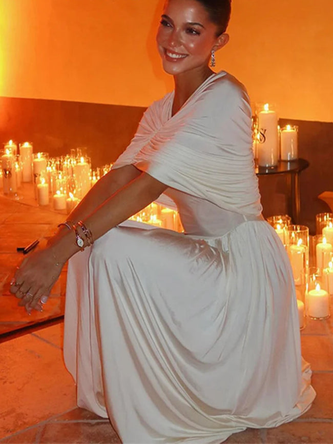 Woman in a white dress sitting in a room with candles, ZAHM brand visible