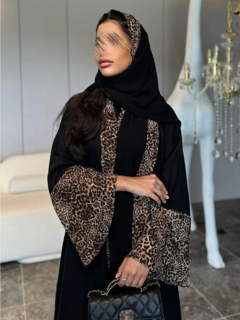 Person wearing a black abaya with leopard print details in an indoor setting.