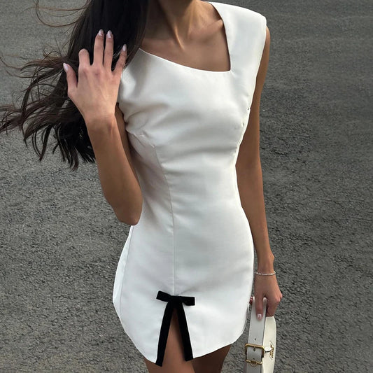 Woman wearing a white dress with a black bow detail on a gray background
