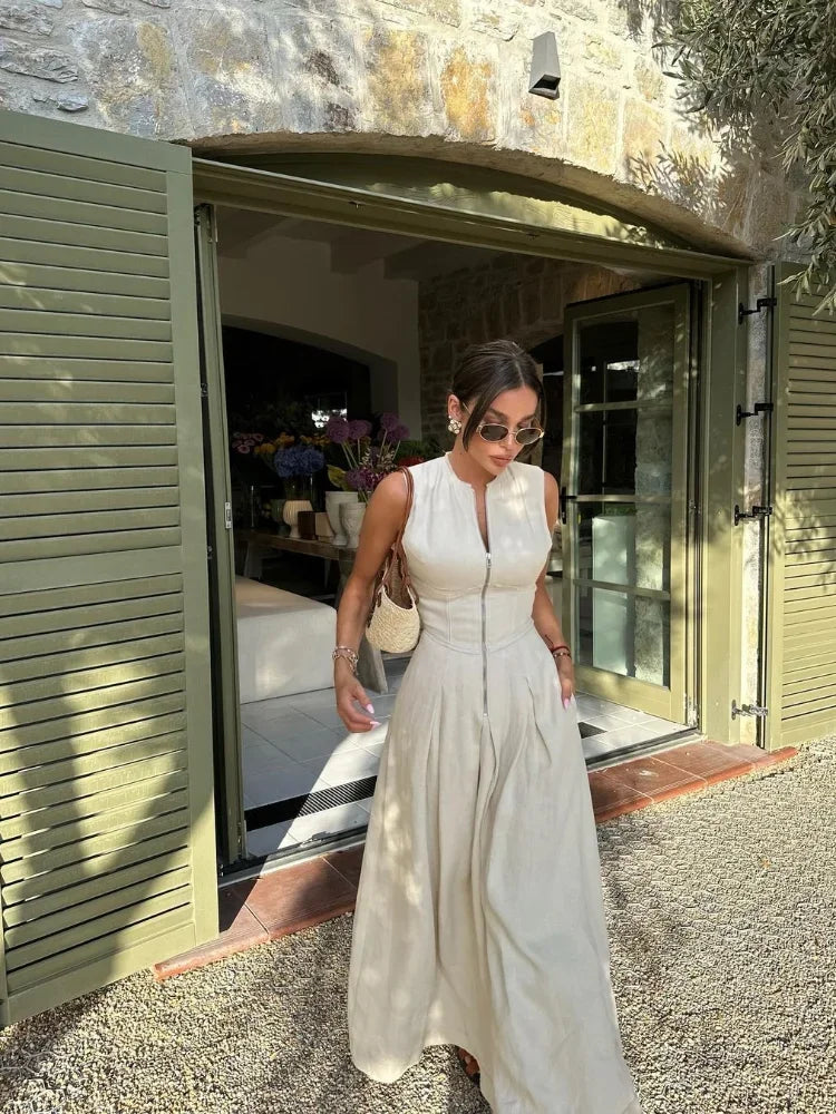 Woman in a white dress standing outside a building with stone walls.